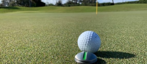 A titleist golf ball in front of an On Point Ball Marker used in a product review by Michael Duranko of GolfToons